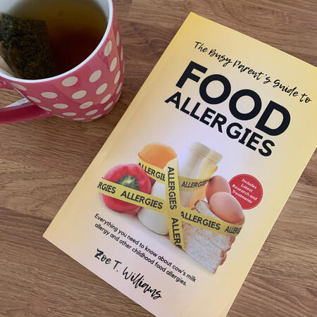 A copy of the book, The Busy Parent's Guide to Food Allergies by Zoe T. Williams, on a kitchen counter with a cup of herbal tea.